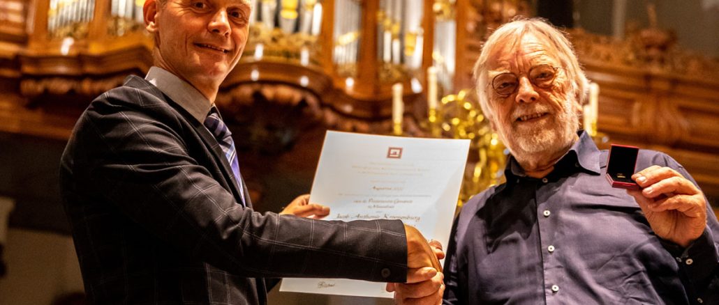 Jaap Kroonenburg (r) ontvangt de onderscheiding uit handen van kerkrentmeester Ko Heijboer