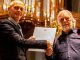 Jaap Kroonenburg (r) ontvangt de onderscheiding uit handen van kerkrentmeester Ko Heijboer